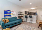 Thumbnail 13 of 16 - A living room with a blue couch and a painting on the wall at Sweetwater Point in Douglasville, GA
