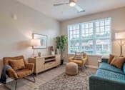 Thumbnail 11 of 16 - A living room with a blue couch, a chair, a table, and a ceiling fan at Sweetwater Point in Douglasville, GA.