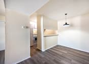 Thumbnail 9 of 14 - A room with a kitchen area and a hanging light fixture.