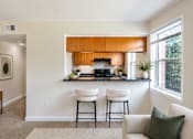 Thumbnail 13 of 14 - A kitchen with a bar stool and a couch.