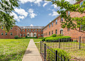Thumbnail 1 of 14 - A long brick building with a walkway in front.
