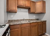 Thumbnail 2 of 30 - A kitchen with wooden cabinets and a white stove.