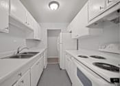 Thumbnail 3 of 30 - A white kitchen with a sink and stove.