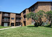 Thumbnail 27 of 30 - A large brick building with a green lawn in front.