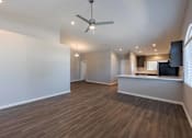 Thumbnail 3 of 15 - A spacious room with a ceiling fan and wooden flooring.