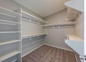Thumbnail 11 of 15 - A walk-in closet with white shelving and a carpeted floor.