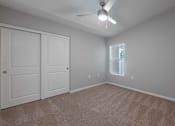 Thumbnail 8 of 15 - A room with a ceiling fan and two doors.