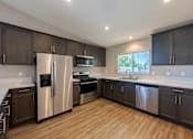 Thumbnail 2 of 15 - A kitchen with dark wood cabinets and stainless steel appliances.