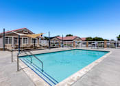 Thumbnail 1 of 15 - A swimming pool surrounded by a fence and a building in the background.