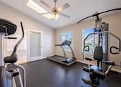 Thumbnail 9 of 15 - A home gym with a treadmill, elliptical trainer, and a stationary bike.