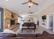 Thumbnail 7 of 15 - A living room with a brown leather couch and a fireplace.