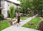 Thumbnail 22 of 22 - a woman walking her dog on a sidewalk at Abby Creek Apartments, California 