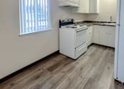 Thumbnail 27 of 34 - Monterey Manor Vacant Apartment dining and kitchen with white cabinets and a stove and vinyl plank floor