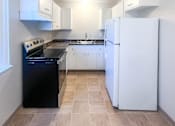 Thumbnail 17 of 34 - Monterey Manor vacant apartment dining and kitchen with cabinets, fridge, stove, and vinyl floor