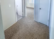 Thumbnail 19 of 34 - Monterey Manor vacant apartment hallway with carpet and two storage closets