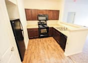 Thumbnail 5 of 34 - A kitchen with a black fridge, black oven, and wooden cabinets.