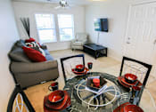 Thumbnail 3 of 19 - A living room with a grey sofa, a glass table with red bowls and a black bicycle.