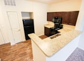 Thumbnail 6 of 34 - A kitchen with a black refrigerator and stove top oven.
