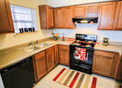 Thumbnail 1 of 19 - A kitchen with a black stove top oven and wooden cabinets.