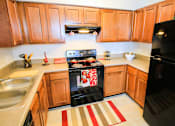 Thumbnail 2 of 19 - A kitchen with wooden cabinets and a black oven.