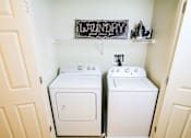 Thumbnail 10 of 19 - A laundry sign is above a washer and dryer in a small room.
