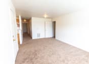 Thumbnail 13 of 14 - An empty living room with a kitchen in the background at Maple Tree Apartments in LaPorte, IN