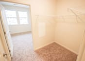 Thumbnail 12 of 34 - A small, empty room with a carpeted floor and a closet with shelves.