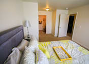 Thumbnail 5 of 19 - A bedroom with a bed, lamp, and a painting on the wall.