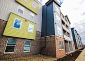 Thumbnail 1 of 34 - A row of modern apartment buildings with a mix of brick and siding exteriors.