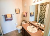 Thumbnail 9 of 19 - A bathroom with a toilet, sink, mirror, and towel rack.