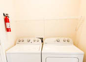 Thumbnail 14 of 34 - Two white front loading washing machines in a small laundry room.