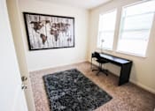 Thumbnail 8 of 34 - A room with a world map on the wall and a black desk with a chair.