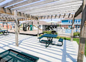 Thumbnail 13 of 19 - A wooden pergola shades a picnic table in a sunny outdoor area.