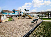 Thumbnail 16 of 19 - A playground with a yellow slide and a green bench.