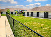 Thumbnail 14 of 19 - A dog park with a black fence with apartment buildings in the background