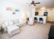 Thumbnail 21 of 34 - A living room with a white couch and a fan.