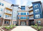 Thumbnail 16 of 34 - A modern apartment complex with multiple balconies and doors.