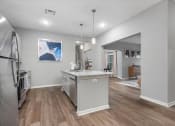 Thumbnail 26 of 42 - the kitchen with an island and living room  at Aurora Luxury Apartments in Madison AL