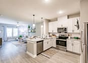 Thumbnail 35 of 94 - an open kitchen and living room with white cabinets and stainless steel appliances