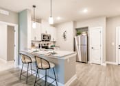 Thumbnail 38 of 94 - an open kitchen with a counter with three stools and a stainless steel refrigerator