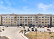 Thumbnail 45 of 58 - A large apartment complex with a parking lot in front.