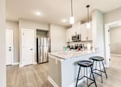 Thumbnail 57 of 94 - a kitchen with a large island with bar stools and a stainless steel refrigerator