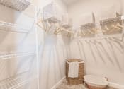 Thumbnail 36 of 57 - a walk in closet with a white shower and a basket on the floor at  a living room with tables and chairs and a ceiling fan at Swiftwater apartments in Port Charlotte, FL