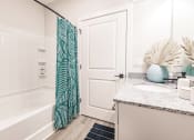 Thumbnail 31 of 57 - a bathroom with a shower and a sink at  a living room with tables and chairs and a ceiling fan at Swiftwater apartments in Port Charlotte, FL