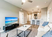 Thumbnail 63 of 94 - a living room with a coffee table, a couch, and a kitchen in the background