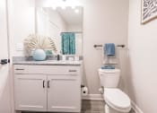 Thumbnail 30 of 57 - a bathroom with a toilet and a sink and a mirror at  a living room with tables and chairs and a ceiling fan at Swiftwater apartments in Port Charlotte, FL