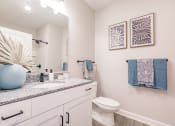 Thumbnail 29 of 57 - a bathroom with a sink and a toilet at  a living room with tables and chairs and a ceiling fan at Swiftwater apartments in Port Charlotte, FL