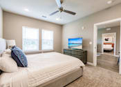 Thumbnail 75 of 94 - a bedroom with a bed, a tv, and two windows at Vantage Luxury Apartments in  Cape Coral, FL
