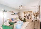 Thumbnail 24 of 57 - a living room with furniture and a ceiling fan and a kitchen in the background at  a living room with tables and chairs and a ceiling fan at Swiftwater luxury apartments in Port Charlotte, FL