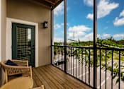 Thumbnail 66 of 94 - a screened in balcony with a view of the ocean and a chair and a table